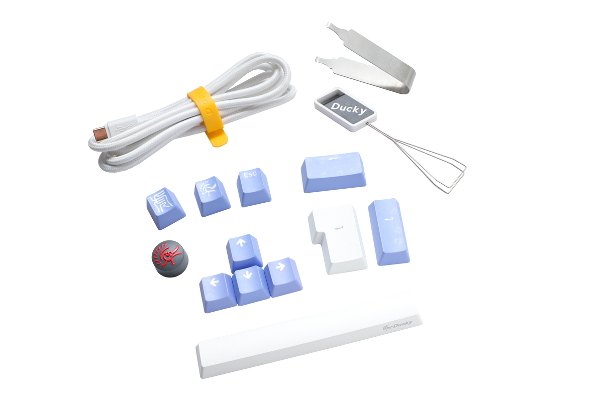 Various Ducky keyboard accessories including a USB cable, keycap puller, and replacement PBT keycaps in blue and white, displayed on a clean, white background.