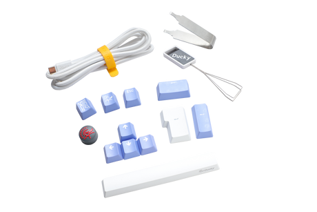 Various Ducky keyboard accessories including a USB cable, keycap puller, and replacement PBT keycaps in blue and white, displayed on a clean, white background.