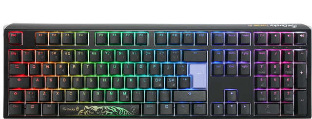 A colorful backlit mechanical gaming keyboard with vibrant rainbow LED lights, featuring a Ducky One 3 - Classic Black / White Nordic - Fullsize - Cherry Red logo on the space bar and a dark gray frame. The keys are laid out in a typical QWERTY configuration.