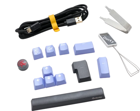 Various computer keyboard accessories on a transparent background, including keycaps, a cable, a keycap puller, and a spacebar for the Ducky One 3 - Classic Black / White Nordic - Fullsize - Cherry Silver, all displaying the "Ducky" brand.