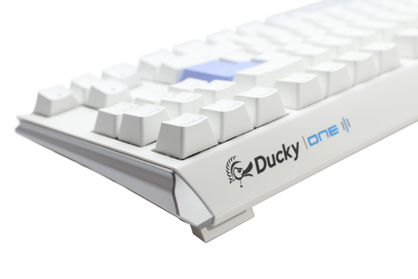 A close-up of a white mechanical keyboard, featuring PBT keycaps and the "Ducky" brand visible on the front side, set against a plain, light gray background.