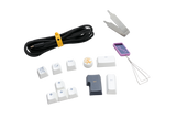 An assortment of Ducky keyboard accessories including a keycap puller, various PBT keycaps with symbols, a coiled cable, and additional small tools, all displayed on a white background.