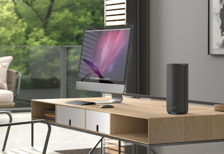 Sort NETGEAR Orbi-enhed placeret ved en computer på et skrivebord